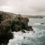 a rocky cliff with waves crashing against it