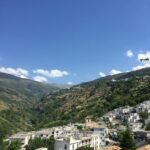 white and brown concrete buildings on green mountain under blue sky during daytime